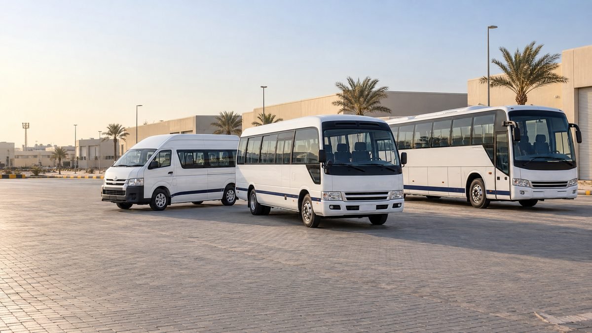 A high-roof passenger van, a coaster minibus and a larger bus parked together on a yard.